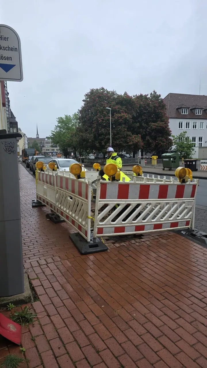 Kopfloch auf einem Gehweg, gesichert mit Absperrung und Baken