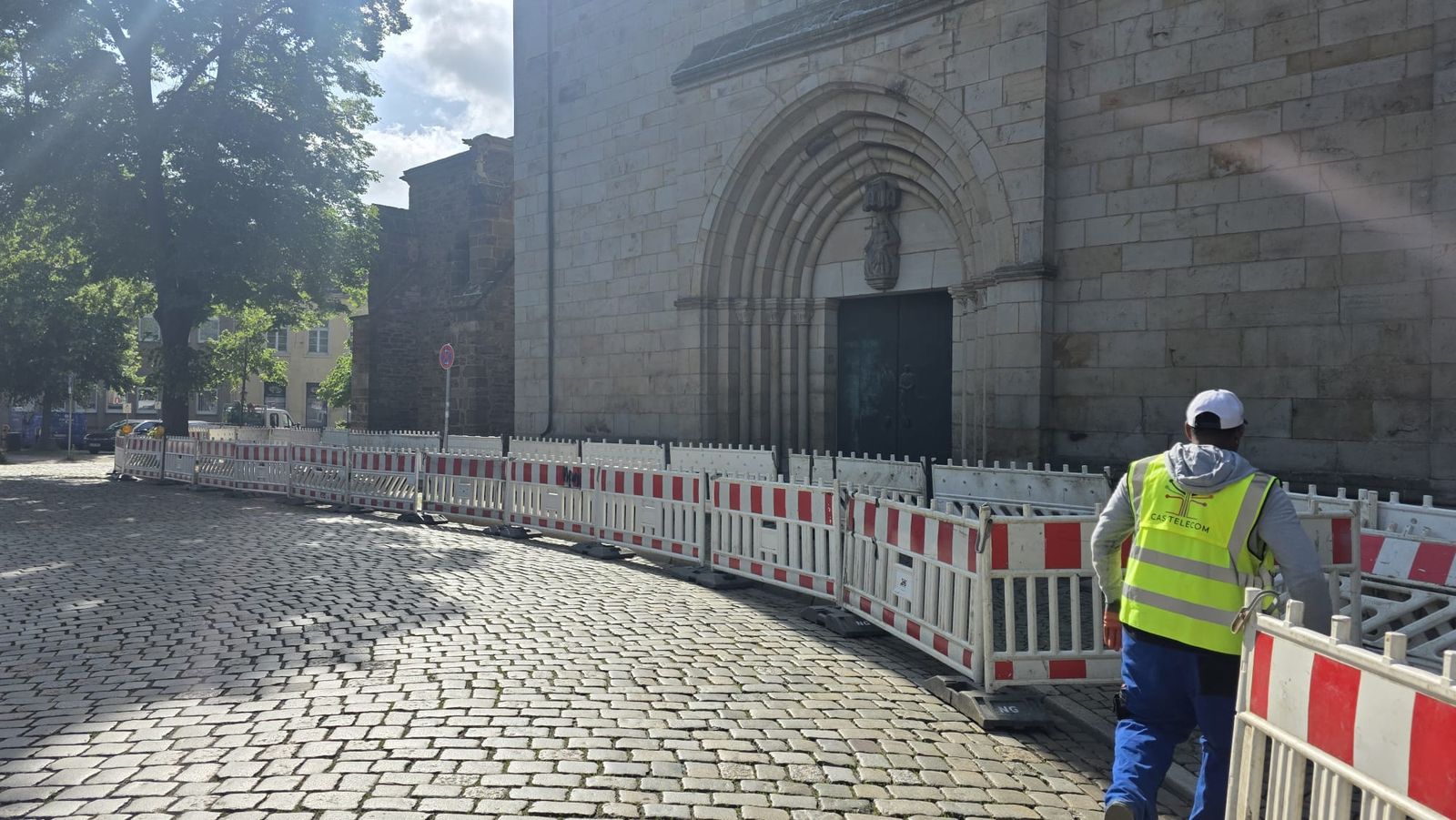 Operario de CAS Telecom junto al vallado de obra frente a la fachada de una iglesia en un casco histórico